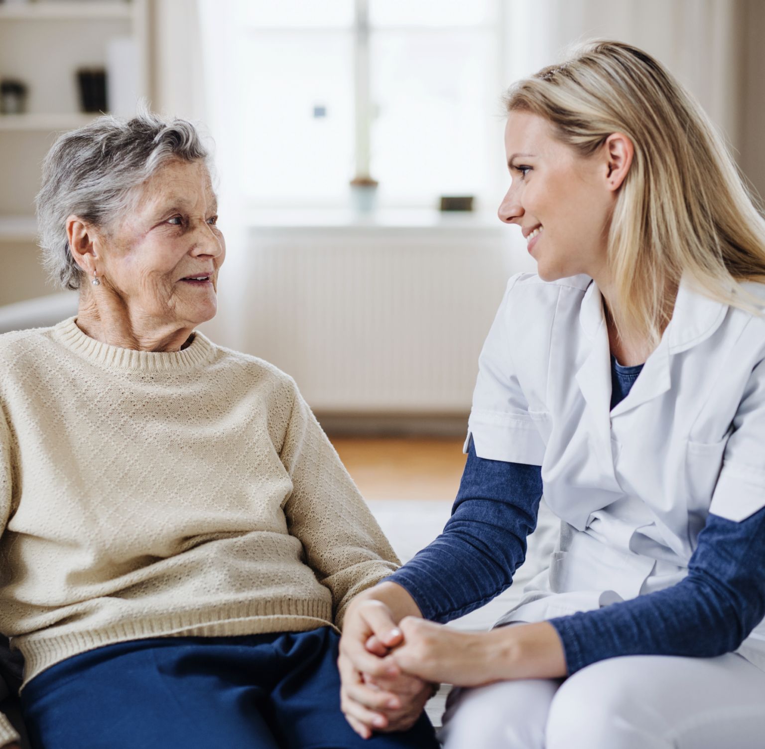 Eine Mitarbeiterin von Agesto hält die Hand einer Seniorin